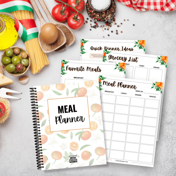 The Clutter Keeper Meal Planner with example pages on a table with kitchen tools and ingredients